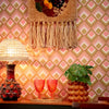 Roomset close-up of vintage, diamond geometric wallpaper in vintage pink and harvest gold colourway
